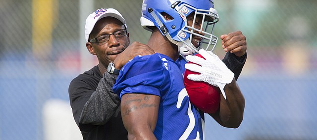Kansas running back coach Reggie Mitchell has some fun with De'Andre Mann as the running backs work together during the first day of practice on Thursday, Aug. 6, 2015 at the fields south of Anschutz Pavilion.