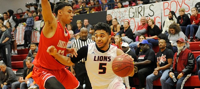 Lawrence High senior Justin Roberts (5) drives against the Shawnee Mission North's Avante Williams (13) during the Indians' 71-62 win Tuesday, February 16, 2016, at LHS.