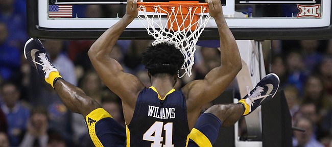West Virginia forward Devin Williams (41) takes his time coming down from the rim after a dunk against Kansas during the first half, Saturday, March 12, 2016 at Sprint Center in Kansas City, Mo.