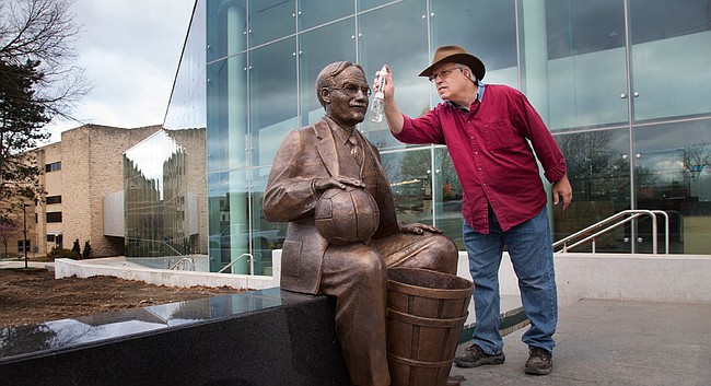Sculptor Kim Tefft puts a finishing touch on a sculpture of James Naismith that was installed Wednesday, March 23, 2016, outside the new DeBruce Center, which will house Naismith's original rules of basketball on the Kansas University campus. Tefft finished the statue that his late father, Elden, created in the early 2000s.