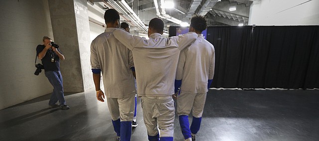 Kansas guard Frank Mason III rests his elbows on the shoulders of teammates Wayne Selden Jr., left, and Devonte' Graham as the starting five make their way toward interviews with media members on Friday, March 25, 2016 at KFC Yum! Center in Louisville, Kentucky.