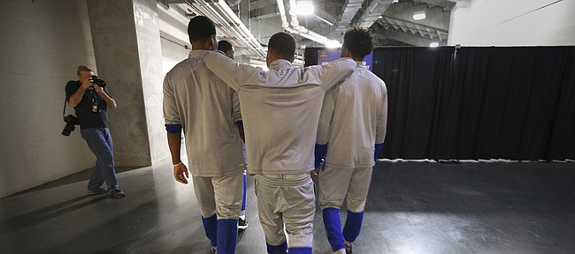 Kansas guard Frank Mason III rests his elbows on the shoulders of teammates Wayne Selden Jr., left, and Devonte' Graham as the starting five make their way toward interviews with media members on Friday, March 25, 2016 at KFC Yum! Center in Louisville, Kentucky.