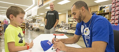 Former Kansas University star forward Perry Ellis signs an autograph for five-year-old Packson McDaniel, of Lawrence, Saturday afternoon at Hy-Vee, 3504 Clinton Parkway.