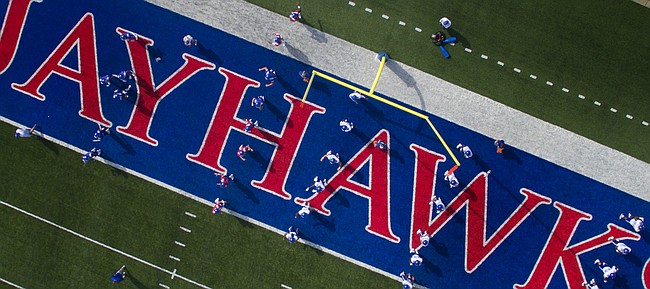 The Kansas Jayhawks, coaches and staff position themselves around the field and in the end zone for stretches during practice on Friday, Aug. 19, 2016 at Memorial Stadium.