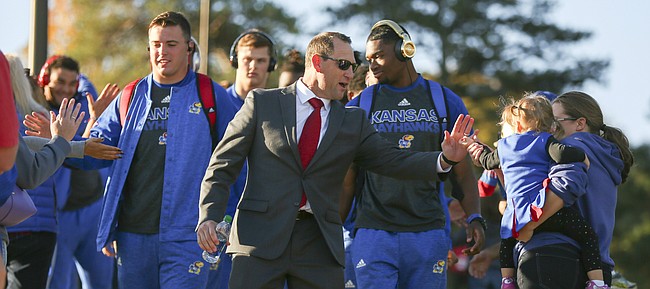 Kansas head coach David Beaty slaps hands with two-year-old Nadia Carrigan, Lawrence, as she greets the Jayhawks with her mother Kristen Carrigan before the game on Saturday, Oct. 22, 2016 at Memorial Stadium.