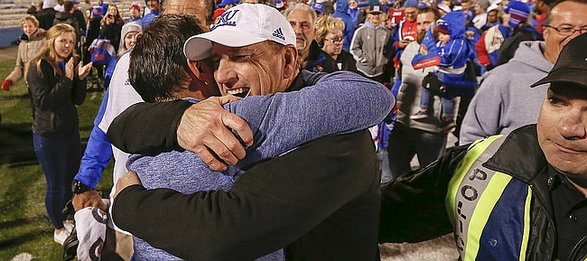 Kansas head coach David Beaty gets a hug from Kansas volleyball head coach Ray Bechard following the Jayhawks' 24-21 overtime upset of Texas on Saturday, Nov. 19, 2016 at Memorial Stadium. Saturday's victory was Beaty's first Big 12 coaching win. Bechard's volleyball team clinched a share of the Big 12 conference title with a win against Iowa State earlier in the day.