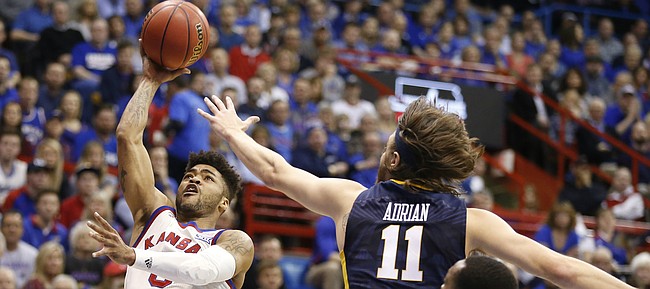 Kansas guard Frank Mason III (0) puts up a shot against West Virginia forward Nathan Adrian (11) during the first half, Monday, Feb. 13, 2017 at Allen Fieldhouse.