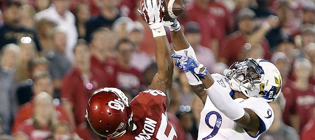 Oklahoma running back Joe Mixon (25) works to make a catch as Kansas safety Fish Smithson (9) defends during the first half of an NCAA college football game in Norman, Okla., Saturday, Oct.29, 2016.
