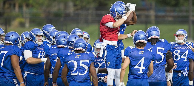 Kansas quarterback Carter Stanley gives a flying bump to running back Kendall Morris, obscured, as the Jayhawks gear up for practice on Friday, Aug. 18, 2017 at the grass fields adjacent to Hoglund Ballpark.