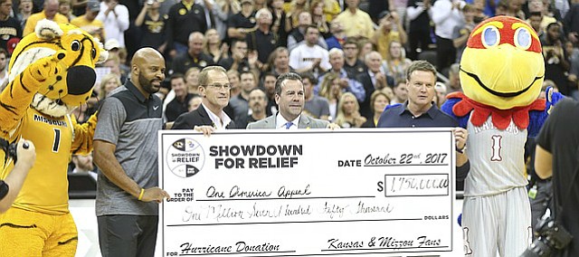 Kansas head coach Bill Self, Missouri head coach Cuonzo Martin, left, Missouri athletic director Jim Sterk and Kansas athletic director Sheahon Zenger hold a ceremonial check for $1.75 million raised for hurricane relief from the Showdown for Relief exhibition, Sunday, Oct. 22, 2017 at Sprint Center in Kansas City, Missouri.