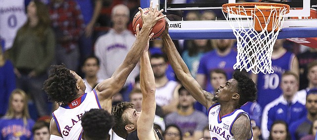 Kansas guard Lagerald Vick (2) and Kansas guard Devonte' Graham, left, stuff a shot from Fort Hays State forward Hadley Gillum (4) during the first half, Tuesday, Nov. 7, 2017 at Allen Fieldhouse.