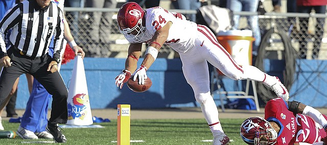 Oklahoma running back Rodney Anderson (24) reaches the ball over the goal line for a touchdown after leaving Kansas safety Tyrone Miller Jr. (22) on the turf during the first quarter on Saturday, Nov. 18, 2017 at Memorial Stadium.
