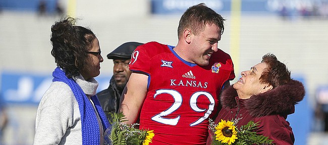 Kansas linebacker Joe Dineen Jr. (29) gets a thank you from Marialuz Cardenas, grandmother of Andre Maloney and Rosaelida Montoya, Maloney's mother after presenting them with flowers during the pregame Senior Day ceremony on Saturday, Nov. 18, 2017 at Memorial Stadium.