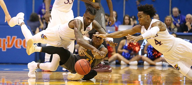 Kansas guard Lagerald Vick, center, and Kansas guard Devonte' Graham (4) dive on a loose ball with Arizona State guard Tra Holder (0) during the second half, Sunday, Dec. 10, 2017 at Allen Fieldhouse.