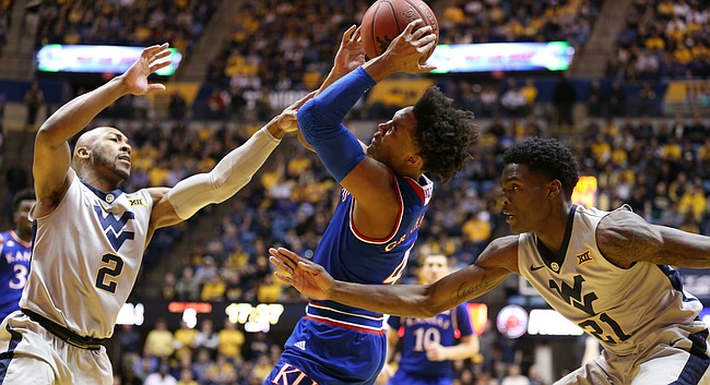 Kansas guard Devonte' Graham (4) is hounded by West Virginia guard Jevon Carter (2) and West Virginia forward Wesley Harris (21) during the first half, Monday, Jan. 15, 2018 at WVU Coliseum in Morgantown, West Virginia.