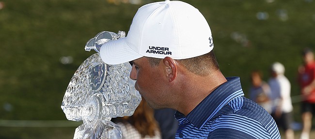 Gary Woodland kisses the championship trophy for photographers after his one-hole playoff win in the final round of the Waste Management Phoenix Open golf tournament Sunday, Feb. 4, 2018, in Scottsdale, Ariz. (AP Photo/Ross D. Franklin)