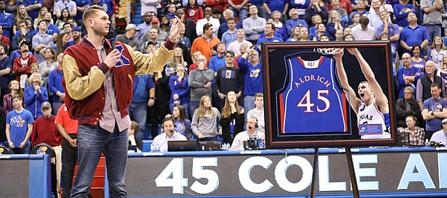 Former Kansas center Cole Aldrich looks up to the rafters where his jersey now hangs during a halftime ceremony.