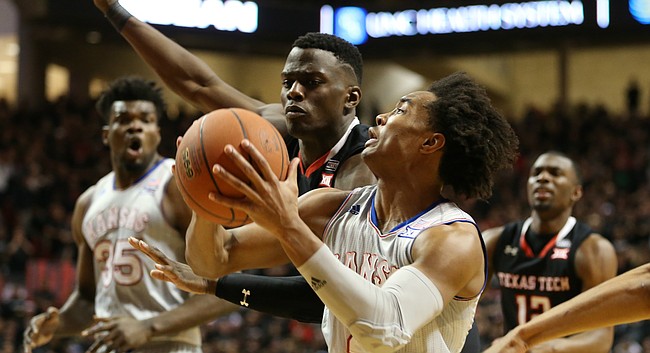 Kansas guard Devonte' Graham (4) gets to the bucket past Texas Tech center Norense Odiase (32) during the first half on Saturday, Feb. 24, 2018 at United Supermarkets Arena.