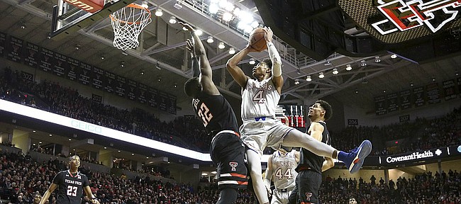 Kansas guard Devonte' Graham (4) puts up a shot and draws a foul from Texas Tech center Norense Odiase (32) during the second half on Saturday, Feb. 24, 2018 at United Supermarkets Arena.