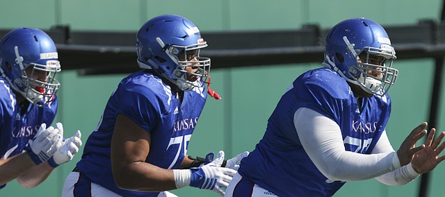 Kansas offensive lineman Andru Tovi, right, Antoine Frazier and Beau Lawrence shuffle through a line of pads during practice on Tuesday, April 10, 2018.