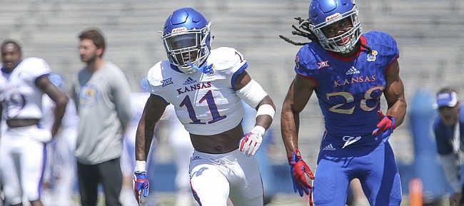 Kansas safety Mike Lee (11) keeps pace with Kansas running back Kendall Morris (28) as Morris runs a route during an open practice on Saturday, April 28, 2018 at Memorial Stadium.