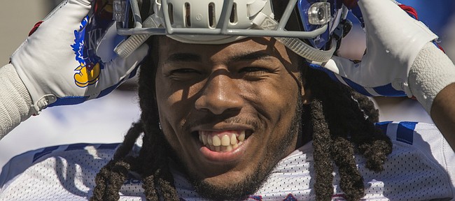 Kansas freshman cornerback Corione Harris smiles as he pulls on his helmet during practice on Monday, April 23, 2018.