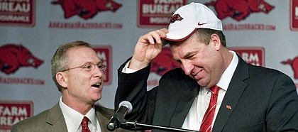 In this Dec. 5, 2012, file photo, Arkansas athletic director Jeff Long, left, presents Bret Bielema with a cap as Bielema is introduced as the school's new head coach during an NCAA college football news conference in Fayetteville, Ark. Kansas named Long its new A.D. on July 5, 2018.  (AP Photo/April L. Brown, File)