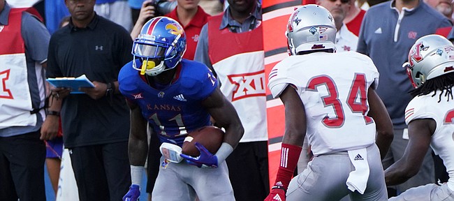 Kansas wide receiver Steven Sims (11) put a move on Nicholls State defensive backs Khristian Mims (34) and Jonavon Lewis (27) during the first half on Saturday, Sept. 1, 2018 at Memorial Stadium.  
