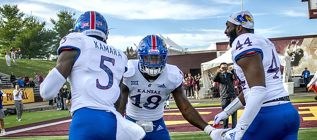 Kansas redshirt junior linebacker Denzel Feaster (18) high-fives junior defensive end Azur Kamara (5) and redshirt junior defensive end Willie McCaleb (44) as they leave the field following the team's 31-7 win over Central Michigan, the program's first road win since 2009.