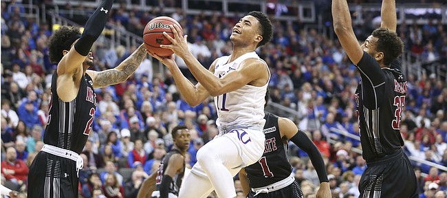 Kansas guard Devon Dotson (11) floats in for a shot between New Mexico State forward Eli Chuha (22) and New Mexico State forward Johnny McCants (35) during the first half on Saturday, Dec. 8, 2018 at Sprint Center.