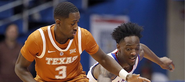 Texas guard Courtney Ramey (3) and Kansas guard Marcus Garrett chase a loose ball during the first half of an NCAA college basketball game Monday, Jan. 14, 2019, in Lawrence, Kan. (AP Photo/Charlie Riedel)