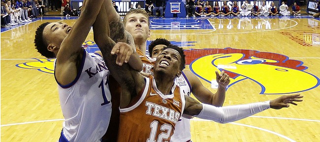 Texas guard Kerwin Roach II (12) and Kansas guard Devon Dotson (11) battle for a rebound during the first half of an NCAA college basketball game Monday, Jan. 14, 2019, in Lawrence, Kan. (AP Photo/Charlie Riedel)