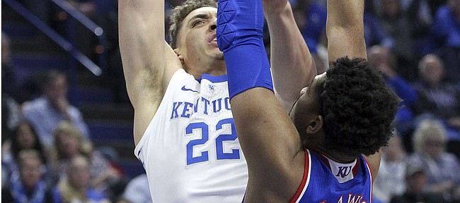 Kentucky's Reid Travis (22) shoots under pressure from Kansas' Dedric Lawson (1) during the first half of an NCAA college basketball game in Lexington, Ky., Saturday, Jan. 26, 2019.