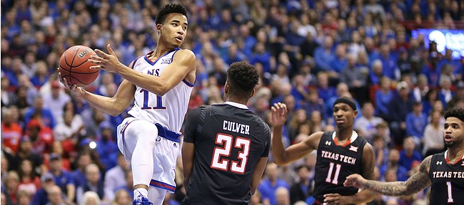 Kansas guard Devon Dotson (11) goes under the bucket as he looks to pass over Texas Tech guard Jarrett Culver (23) during the first half, Saturday, Feb. 2, 2019 at Allen Fieldhouse.