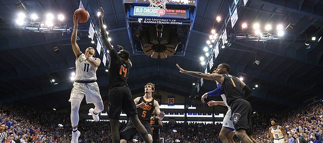 Kansas guard Devon Dotson (11) gets in for a bucket against Oklahoma State forward Yor Anei (14) during the second half, Saturday, Feb. 9, 2019 at Allen Fieldhouse.