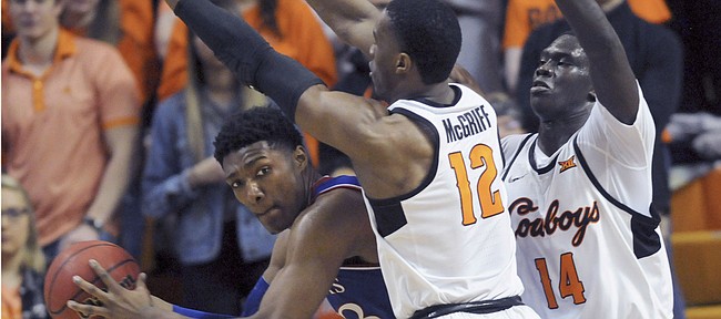 Kansas forward David McCormack, left, looks for an open teammate while under pressure from Oklahoma State forwards Cameron McGriff, center, and Yor Anei during an NCAA college basketball game in Stillwater, Okla., Saturday, March 3, 2019. (AP Photo/Brody Schmidt)