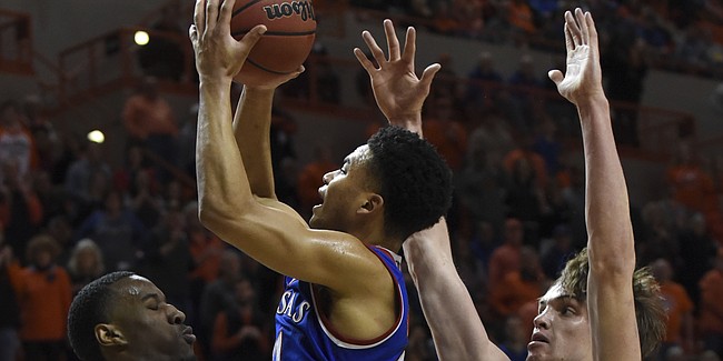 Oklahoma State forward Cameron McGriff, left, takes a charge from Kansas guard Devon Dotson, center, while being pressured by Oklahoma State forward Duncan Demuth during an NCAA college basketball game in Stillwater, Okla., Saturday, March 3, 2019. Kansas defeated Oklahoma State 72-67. (AP Photo/Brody Schmidt)