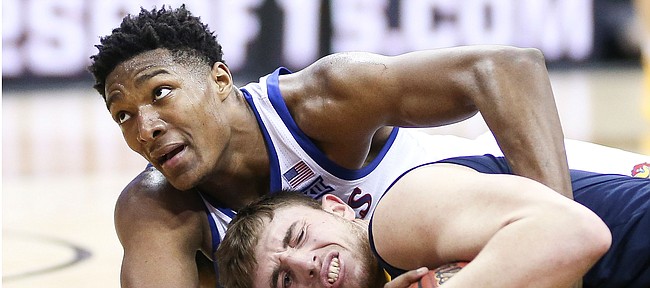 Kansas forward David McCormack (33) ties up a ball with West Virginia forward Logan Routt (31) during the second half, Friday, March 15, 2019 at Sprint Center in Kansas City, Mo.