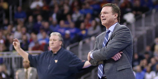 Kansas head coach Bill Self and West Virginia head coach Bog Huggins, background, watch from the sidelines during the second half, Friday, March 15, 2019 at Sprint Center in Kansas City, Mo.