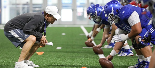 Kansas head coach Les Miles gets down as he works with the offensive line on Thursday, April 4, 2019 at the indoor practice facility.