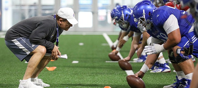 Kansas head coach Les Miles gets down as he works with the offensive line on Thursday, April 4, 2019 at the indoor practice facility.