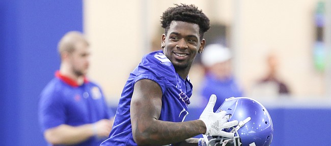 Kansas receiver Daylon Charlot smiles as he puts on his helmet while running to a drills station during football practice on Wednesday, March 6, 2019 within the new indoor practice facility.
