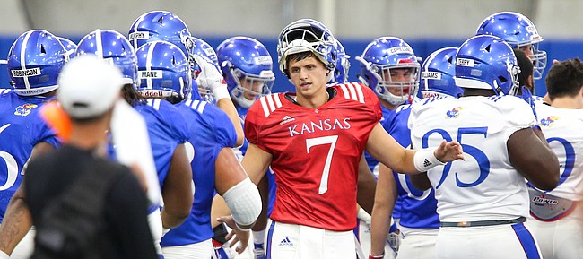 Kansas quarterback Thomas MacVittie high fives his teammates after breaking from a team huddle during practice on Thursday, Aug. 8, 2019.
