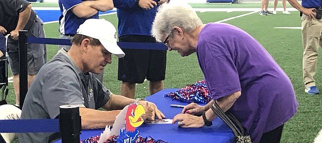 Kansas football coach Les Miles signs an autograph for Vicky Mall, of Clay Center, on Saturday, Aug. 10, 2019, during the team's Fan Day, at the indoor practice facility.