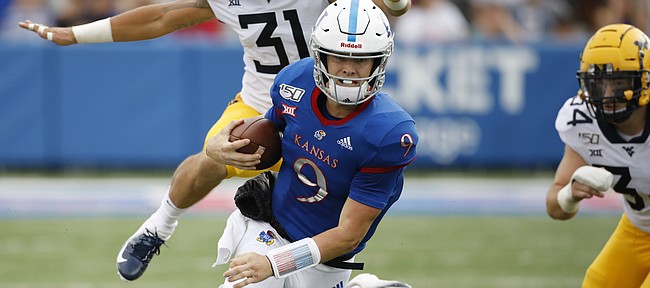 Kansas quarterback Carter Stanley (9) scrambles for a first down as he slips past West Virginia safety Jovanni Stewart (9) linebacker Zach Sandwisch (31) and linebacker Shea Campbell (34) during an NCAA football game on Saturday, Sept. 21, 2019 in Lawrence, Kan. (AP Photo/Colin E. Braley)