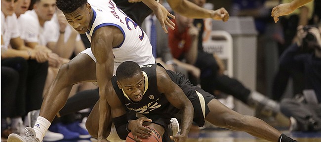 Kansas' Ochai Agbaji, left, and Colorado's McKinley Wright IV chase the ball during the first half of an NCAA college basketball game Saturday, Dec. 7, 2019, in Lawrence, Kan. (AP Photo/Charlie Riedel)
