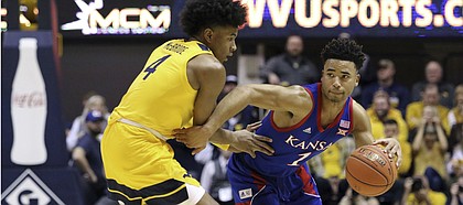 Kansas guard Devon Dotson (1) is defended by West Virginia guard Miles McBride (4) during the first half of an NCAA college basketball game Wednesday, Feb. 12, 2020, in Morgantown, W.Va. (AP Photo/Kathleen Batten)