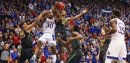 Kansas guard Ochai Agbaji (30) gets tangled with Baylor guard Jared Butler (12) and Baylor forward Tristan Clark (25) while competing for a rebound during the first half on Saturday, Jan. 11, 2020 at Allen Fieldhouse.