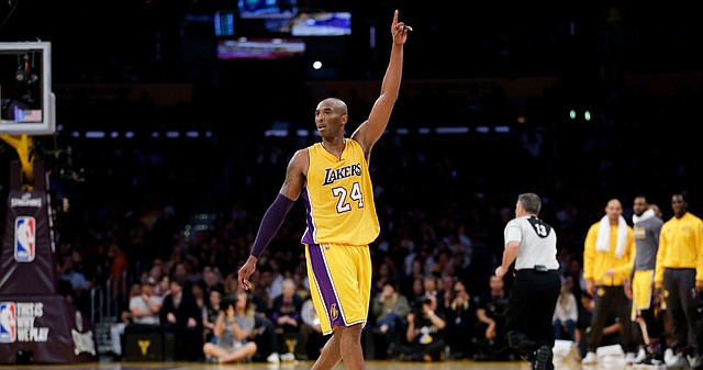 Los Angeles Lakers forward Kobe Bryant gestures during the first half of Bryant's last NBA basketball game, against the Utah Jazz, on Wednesday, April 13, 2016, in Los Angeles. Former Kansas forward Tarik Black, standing in a gray T-Shirt on the Lakers bench, is in the background. 