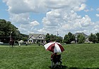 A volunteer uses an umbrella while watching golfers pass on the seventh fairway during the second round of the Travelers Championship golf tournament at TPC River Highlands, Friday, June 26, 2020, in Cromwell, Conn.